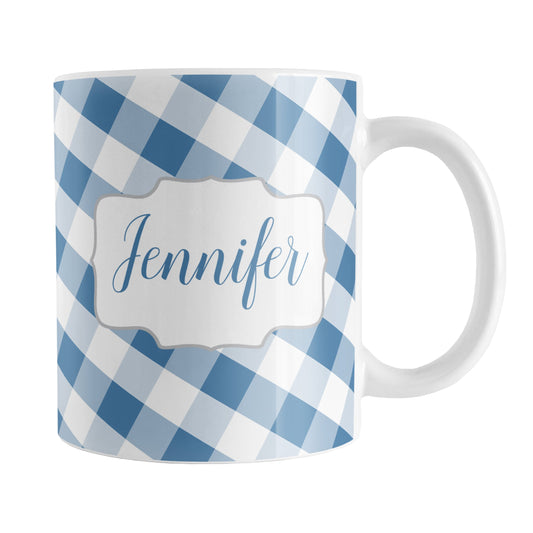 Personalized Blue Gingham Mug (11oz) at Amy's Coffee Mugs. A ceramic coffee mug designed with a slanted blue and white gingham pattern that wraps around the mug up to the handle. Your personalized name is custom-printed in a blue script font on both sides of the mug over the gingham pattern.