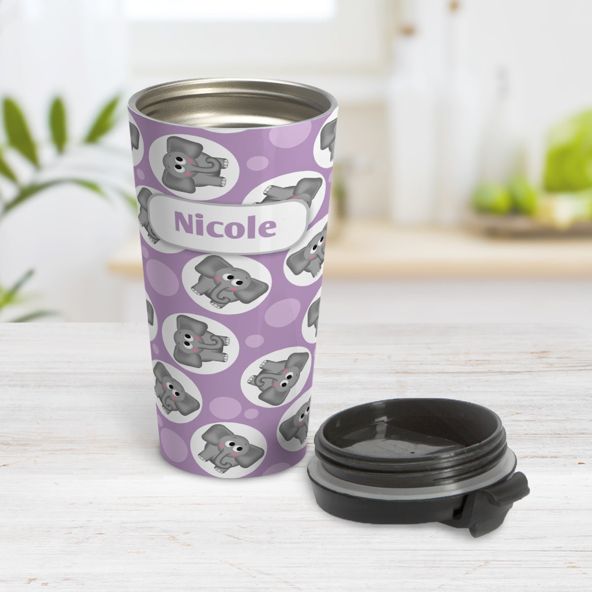 Personalized Cute Purple Elephant Pattern Travel Mug (15oz) at Amy's Coffee Mugs. A travel mug designed with cute and affectionate gray elephants in white circles scattered over a purple background color in a pattern that wraps around the travel mug. Your name is custom printed in purple on white positioned over the elephant pattern. Photo show the mug open on a table with its lid next to it.