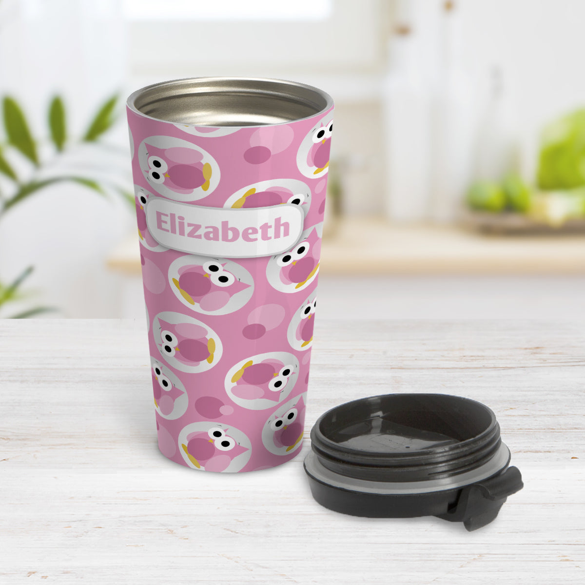 Personalized Funny Cute Pink Owl Pattern Travel Mug (15oz, stainless steel insulated) at Amy's Coffee Mugs. A travel mug designed with a pattern of funny and cute pink owls in a light gray circles scattered over a pink background color that wraps around the travel mug. Your name is printed in pink in a white rectangular frame design over owl pattern. Photo shows the mug open on a table with its lid beside it.
