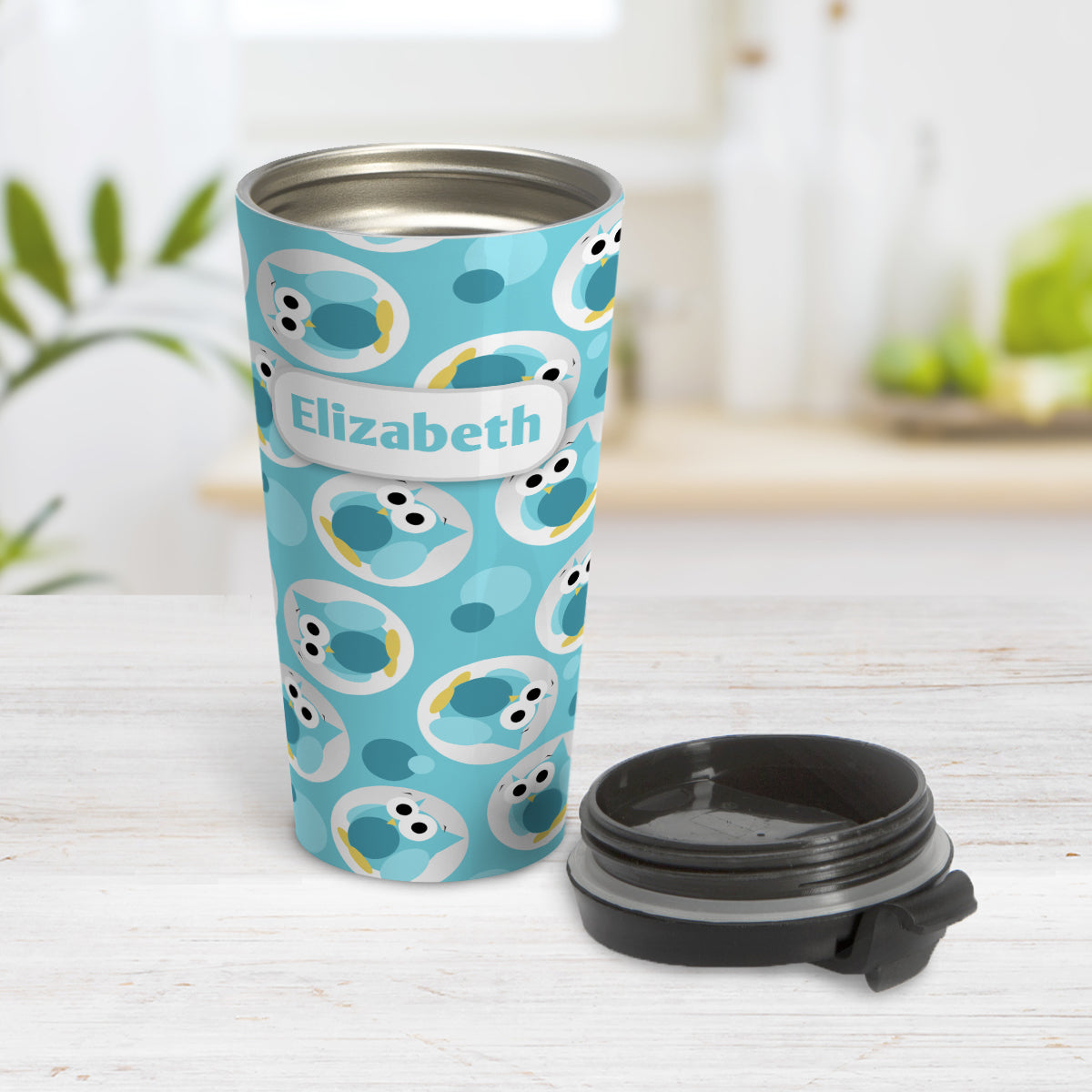 Personalized Funny Cute Turquoise Owl Pattern Travel Mug (15oz) at Amy's Coffee Mugs. A travel mug designed with a pattern of funny and cute turquoise owls in a light gray circles scattered over a turquoise background color that wraps around the travel mug. Your name is printed in turquoise in a white rectangular frame design over the owl pattern. Photo shows the mug open on a table with its lid beside it.