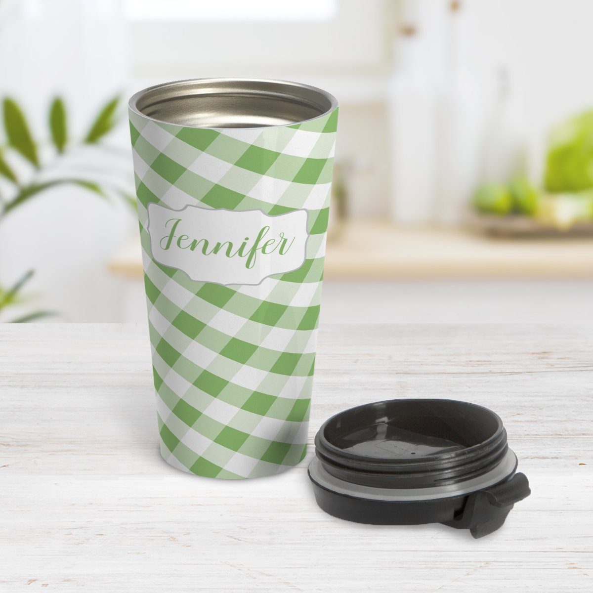 Personalized Green Gingham Travel Mug at Amy's Coffee Mugs. A travel mug designed with a slanted green and white gingham pattern that wraps around the travel mug. Your personalized name is custom-printed in a green script font in a white frame design over the gingham pattern. Photo shows the mug open on a table with its lid beside it.