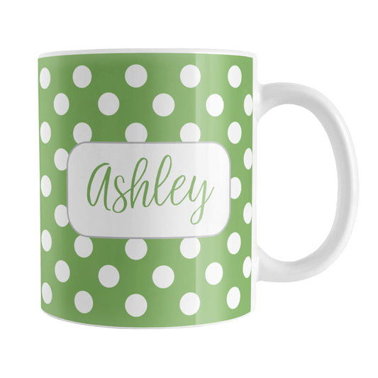 Personalized Green Polka Dot Mug (11oz) at Amy's Coffee Mugs. A ceramic coffee mug designed with a pattern of white polka dots over a green background color that wraps around the mug up to the handle. Your name is personalized in a cute green script font in a white frame design on both sides of the mug over the polka dot pattern.