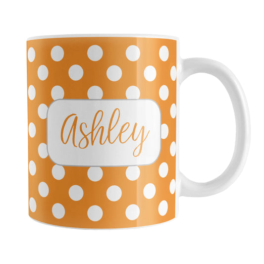 Personalized Orange Polka Dot Mug (11oz) at Amy's Coffee Mugs. A ceramic coffee mug designed with a pattern of white polka dots over an orange background color that wraps around the mug up to the handle. Your name is personalized in a cute orange script font in a white frame design on both sides of the mug over the polka dot pattern.