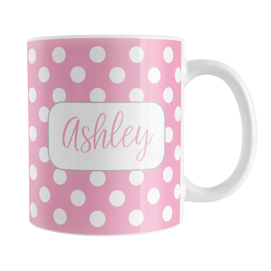 Personalized Pink Polka Dot Mug (11oz) at Amy's Coffee Mugs. A ceramic coffee mug designed with a pattern of white polka dots over a pink background color that wraps around the mug up to the handle. Your name is personalized in a cute pink script font in a white frame design on both sides of the mug over the polka dot pattern.