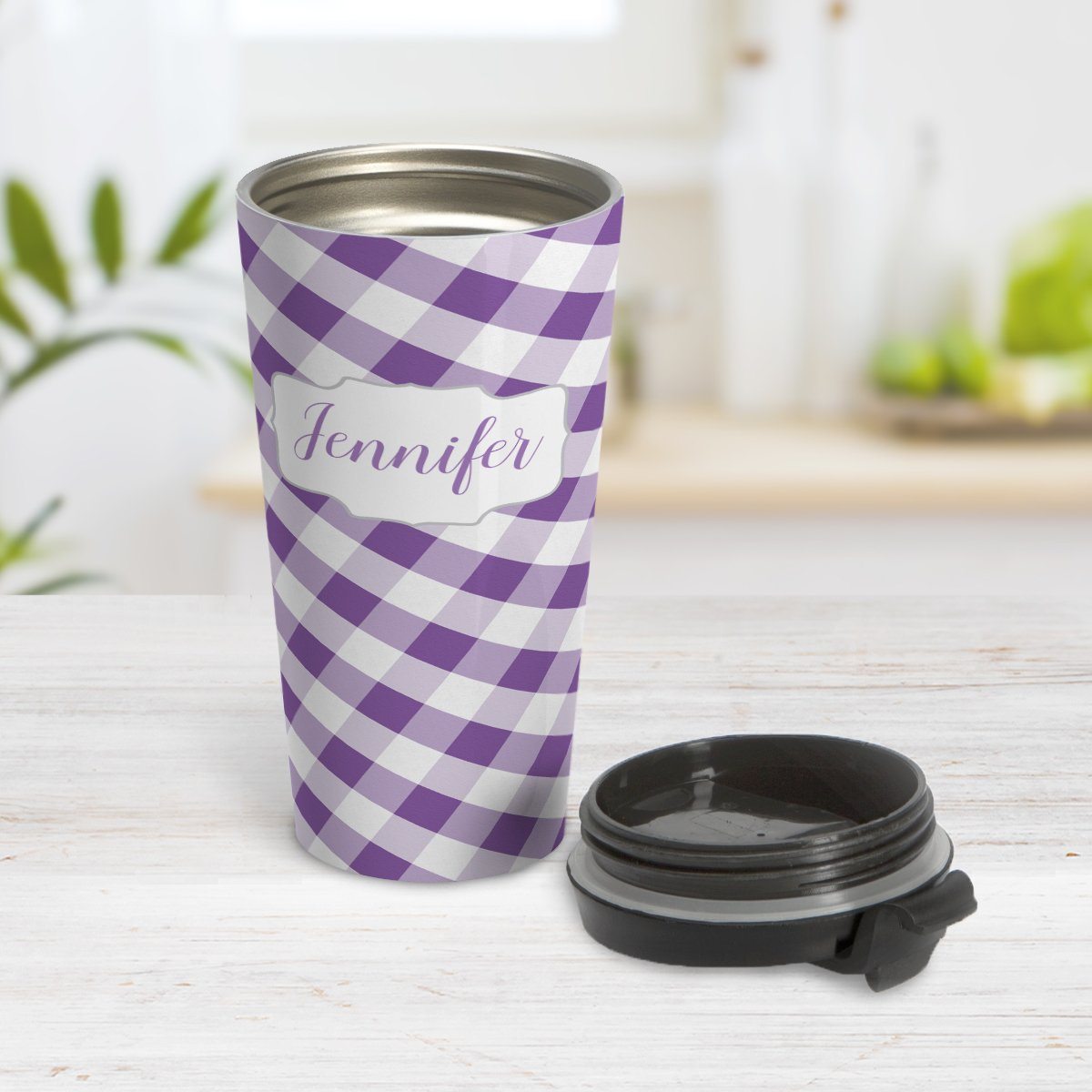Personalized Purple Gingham Travel Mug at Amy's Coffee Mugs. A travel mug designed with a slanted purple and white gingham pattern that wraps around the travel mug. Your personalized name is custom-printed in a purple script font in a white frame design over the gingham pattern. Photo shows the mug open on a table with its lid beside it.