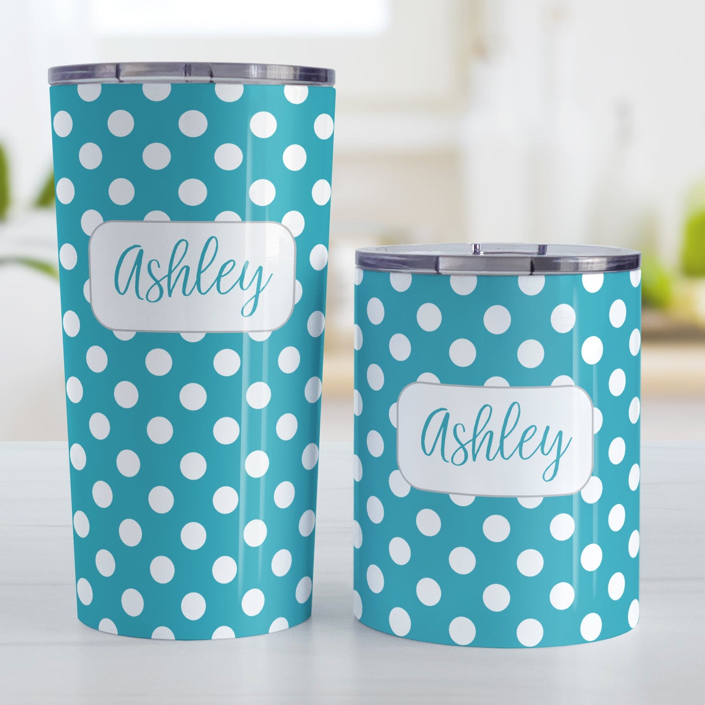 Personalized Turquoise Polka Dot Tumbler Cup (20oz and 10oz, stainless steel insulated) at Amy's Coffee Mugs. A tumbler cup designed with a pattern of white polka dots over a turquoise background color that wraps around the cup. Your name is personalized in a cute turquoise script font in a white frame design over the polka dot pattern. Photo shows both sized cups on a table next to each other.