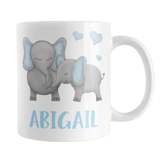 Personalized Watercolor Blue Mommy and Baby Elephants Mug (11oz) at Amy's Coffee Mugs. A ceramic coffee mug designed with affectionate blue and gray mommy and baby elephants illustrated in a watercolor design with blue hearts above them on both sides of the mug. Your personalized name is custom-printed in a cute uppercase-letters font in blue below these adorable elephants.