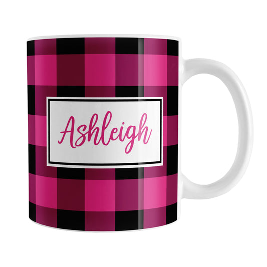Pink and Black Personalized Name Buffalo Plaid Mug (11oz) at Amy's Coffee Mugs. A ceramic coffee mug designed with a raspberry pink and black buffalo plaid (buffalo check) pattern that wraps around the mug up to the handle. Your name is printed in a raspberry pink script font in a white frame design on both sides of the mug over the buffalo plaid background.