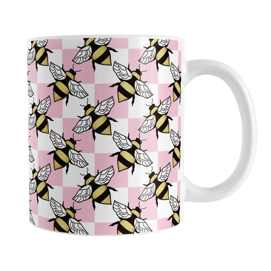 Pink Checkered Bee Mug (11oz) at Amy's Coffee Mugs. A ceramic coffee mug designed with a pink and white checkered pattern adorned with alternately facing bees over the check pattern. This design wraps around the mug up to the handle.