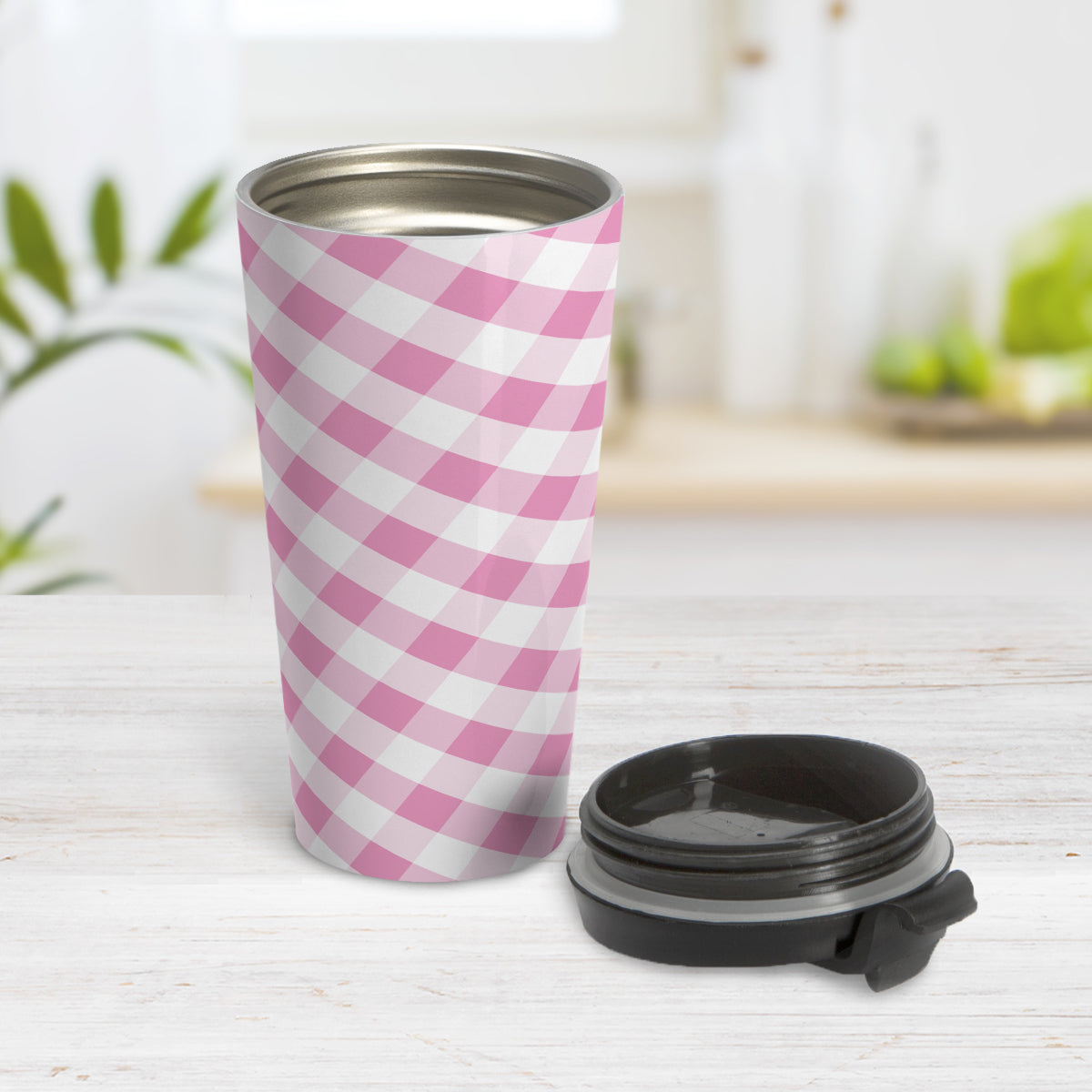 Pink Gingham Travel Mug (15oz) at Amy's Coffee Mugs. A travel mug designed with a slanted pink and white gingham pattern that wraps around the travel mug. Photo shows the mug open on a table with its lid beside it.