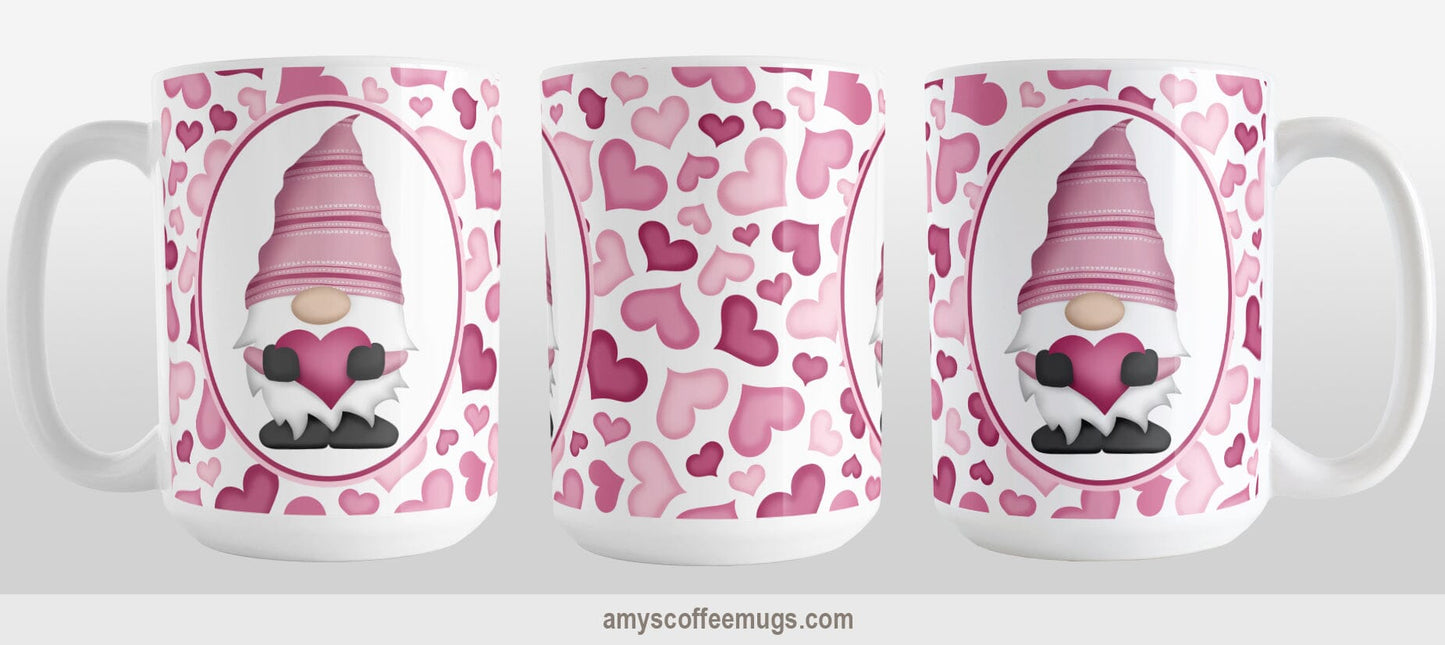 Pink Gnome Hearts Mug (15oz) at Amy's Coffee Mugs. A ceramic coffee mug designed with an adorable pink gnome in a white oval on both sides of the mug over a pattern of cute hearts in different shades of pink that wrap around the mug to the handle. The photo shows 3 sides of the mug design.