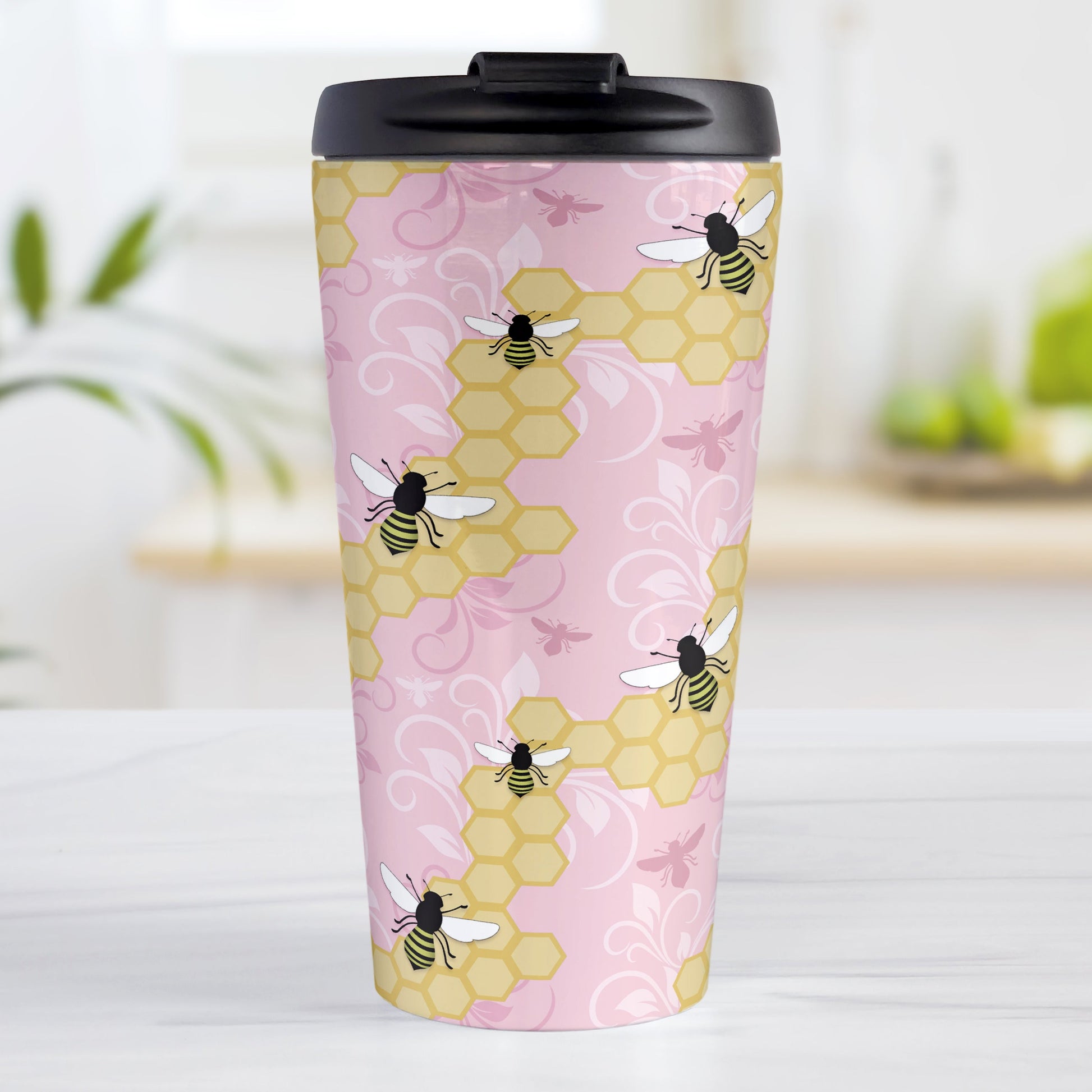 Pink Honeycomb Bee Travel Mug (15oz, stainless steel insulated) at Amy's Coffee Mugs. A travel mug designed with a pattern of black and yellow bees on honeycomb lines over a pink flourish background that wraps around the tapered shaped mug.
