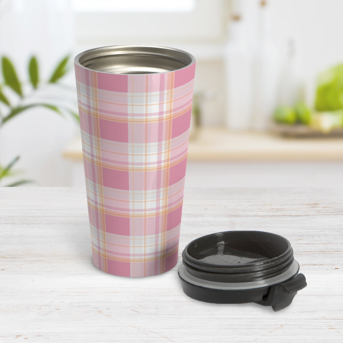 Pink Orange Plaid Travel Mug (15oz, stainless steel insulated) at Amy's Coffee Mugs. A travel mug designed with a fashionable plaid pattern with varying shades of pink with orange accents that wraps around the mug. Photo shows mug open on a table with its lid beside it.