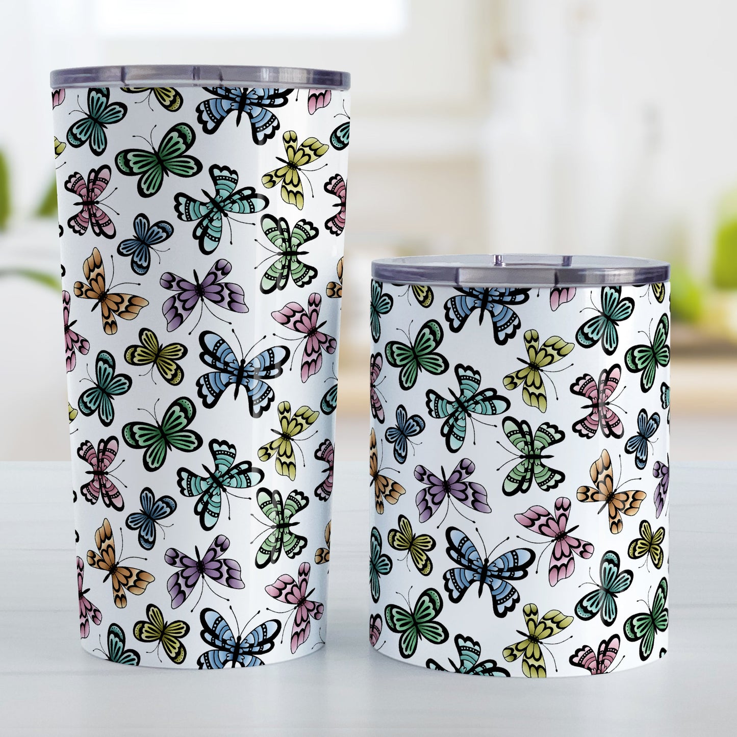 Pretty Butterfly Pattern Tumbler Cup (20oz or 10oz) at Amy's Coffee Mugs. Stainless steel tumbler cups designed with pretty and colorful butterflies in a pattern that wraps around the cups. These tumbler cups are perfect for people who love butterflies and colorful nature designs. Photo shows both sized cups next to each other.