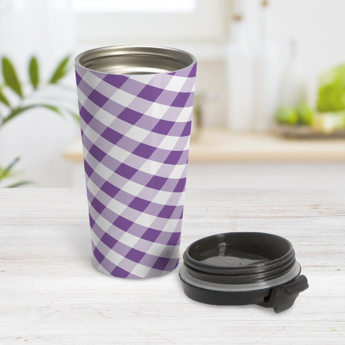 Purple Gingham Travel Mug (15oz) at Amy's Coffee Mugs. A travel mug designed with a slanted purple and white gingham pattern that wraps around the travel mug. Photo shows the mug open on a table with its lid beside it.
