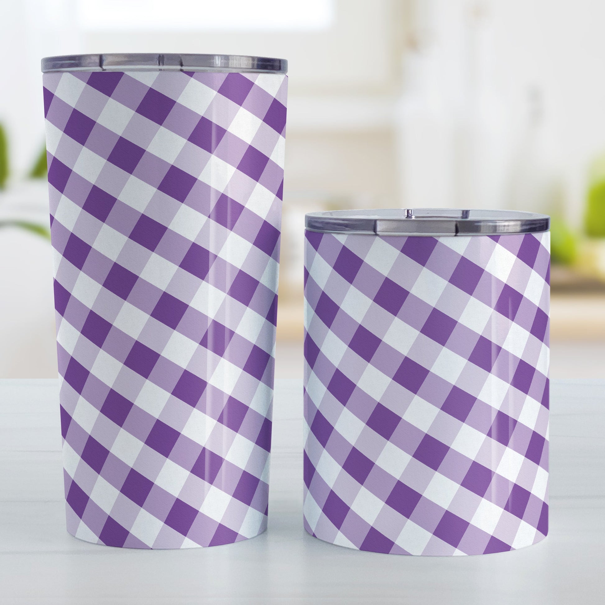 Purple Gingham Tumbler Cup (20oz and 10oz, stainless steel insulated) at Amy's Coffee Mugs. A tumbler cup designed with a slanted purple and white gingham pattern that wraps around the cup. Photo shows both sized cups on a table next to each other.