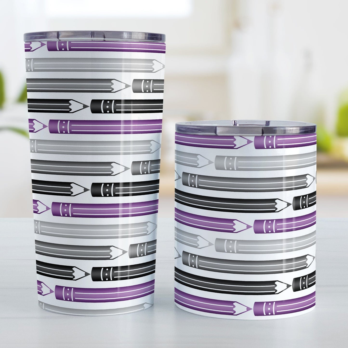 Purple Gray Black Pencils Pattern Tumbler Cups (20oz or 10oz) at Amy's Coffee Mugs. Stainless steel tumbler cups designed with horizontal pencils in purple, gray, and black, stacked in a pattern that wraps around the cup. Photo shows both sized cups on a table next to each other.