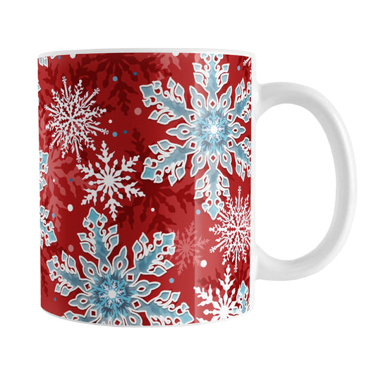 Red Blue Snowflake Pattern Winter Mug (11oz) at Amy's Coffee Mugs. A ceramic coffee mug designed with a pattern of blue and white snowflakes over a red background color that wraps around the mug up to the handle.
