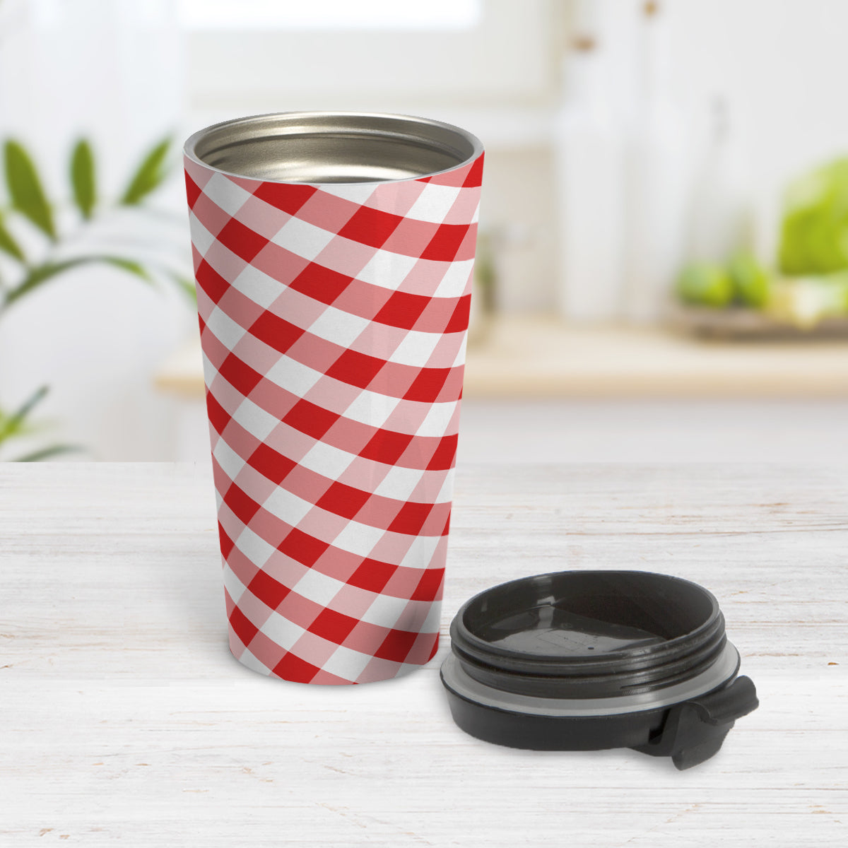 Red Gingham Travel Mug (15oz) at Amy's Coffee Mugs. A travel mug designed with a slanted red and white gingham pattern that wraps around the travel mug. Photo shows the mug open on a table with its lid beside it.