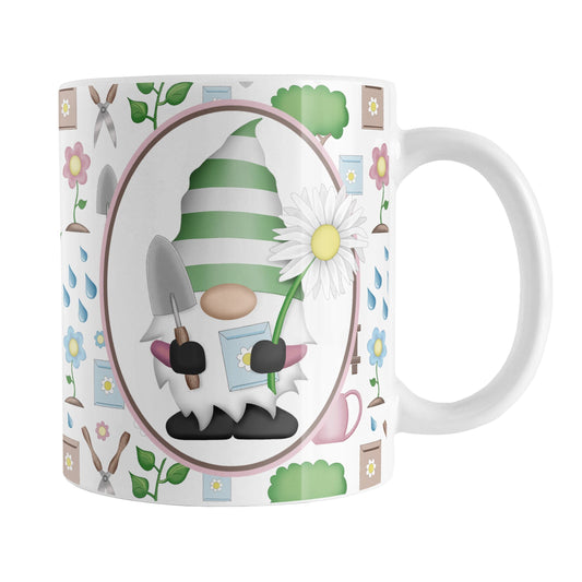 Spring Gnome Gardening Pattern Mug (11oz) at Amy's Coffee Mugs. A ceramic coffee mug designed with an adorable spring gardening gnome holding  an oversized daisy in a white oval over a springtime gardening pattern with trees, plants, flowers, seed packets, watering cans, fences, and gardening tools in spring colors such as pink, blue, green, and brown.