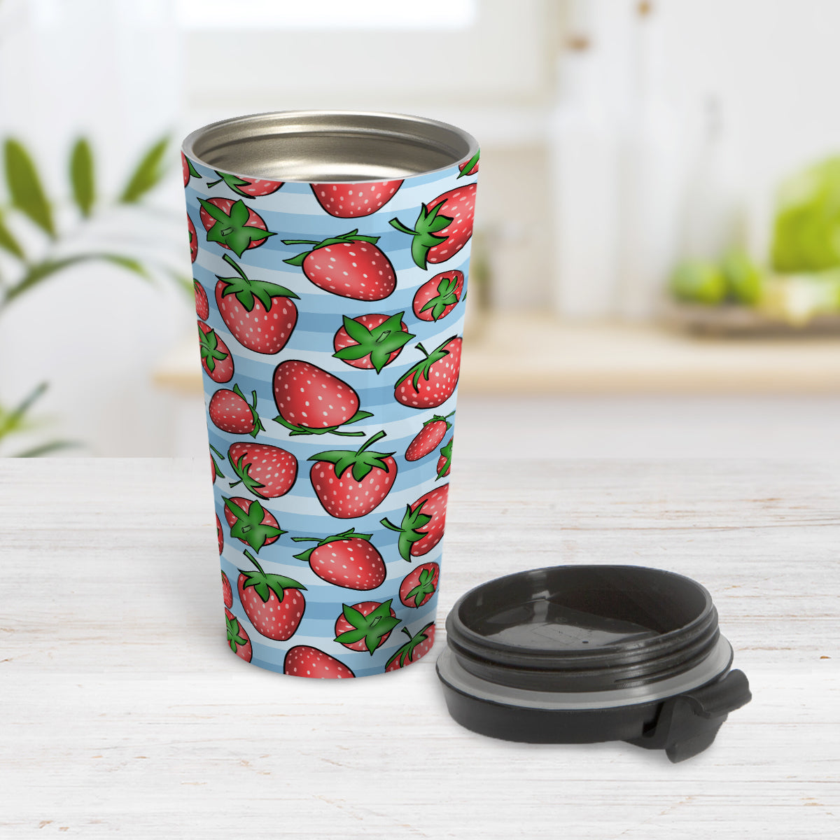 Strawberries on Blue Stripes Travel Mug (15oz) at Amy's Coffee Mugs. A travel mug featuring a print of hand-drawn strawberries in red and green in an assorted pattern over a blue stripes background that wraps around the mug. Photo shows the the mug open on a table with its lid beside it.
