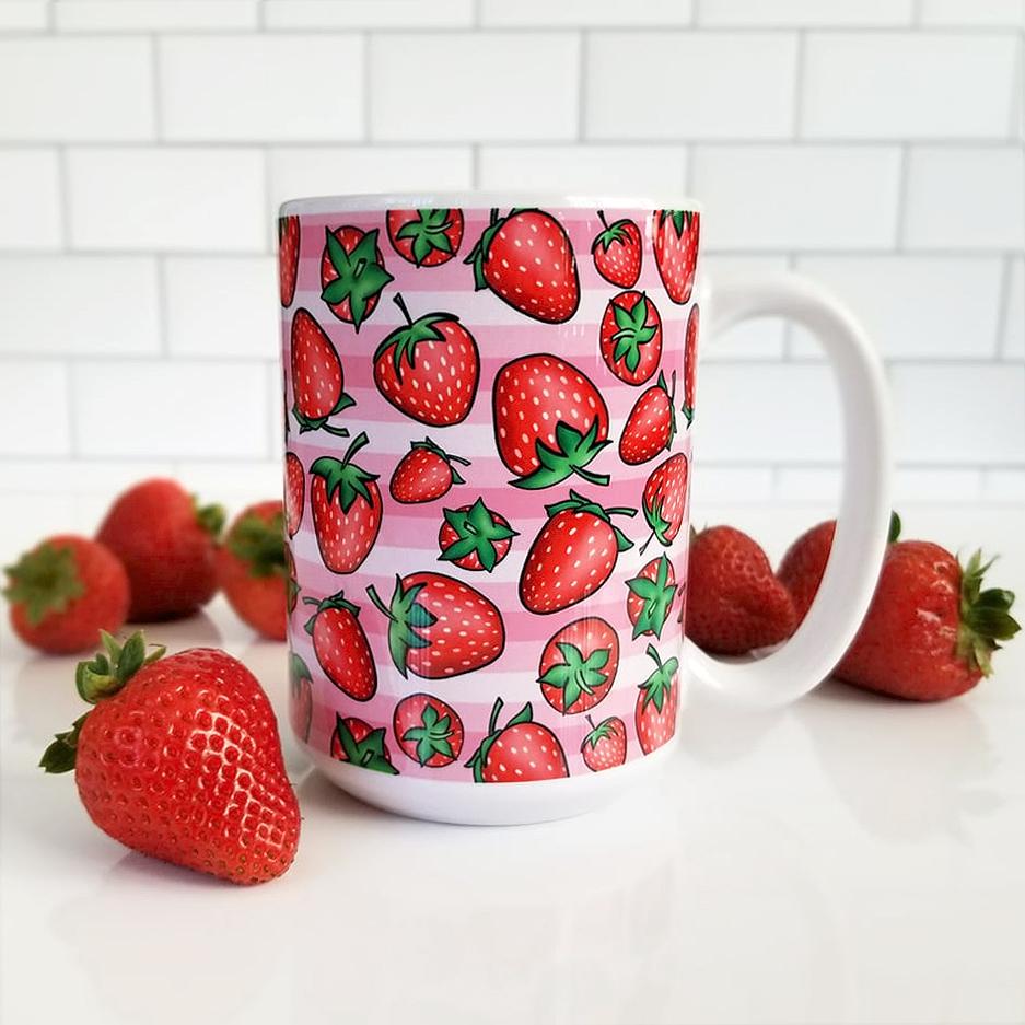 Strawberries on Pink Stripes Mug (15oz) with subway tile and white background and strawberries. - Amy's Coffee Mugs. A ceramic coffee mug featuring a print of hand-drawn strawberries in red and green in an assorted pattern over a pink stripes background that wraps around the mug up to the handle.