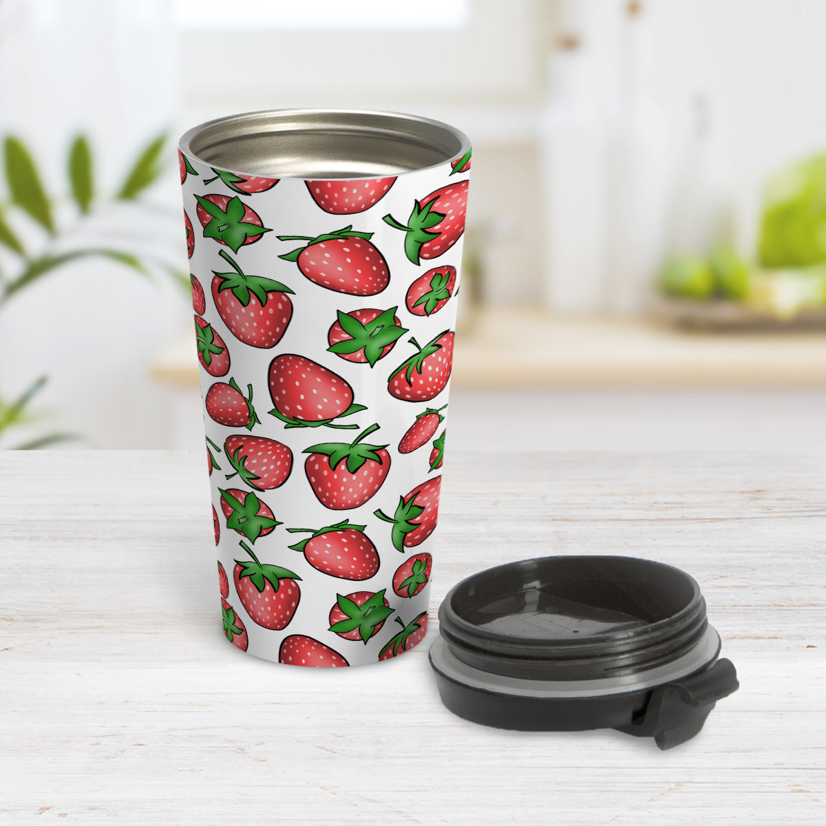 Strawberries Travel Mug (15oz) at Amy's Coffee Mugs. A travel mug featuring a print of hand-drawn strawberries in red and green in an assorted pattern that wraps around the mug. Photo shows the mug open on a table with its lid beside it.