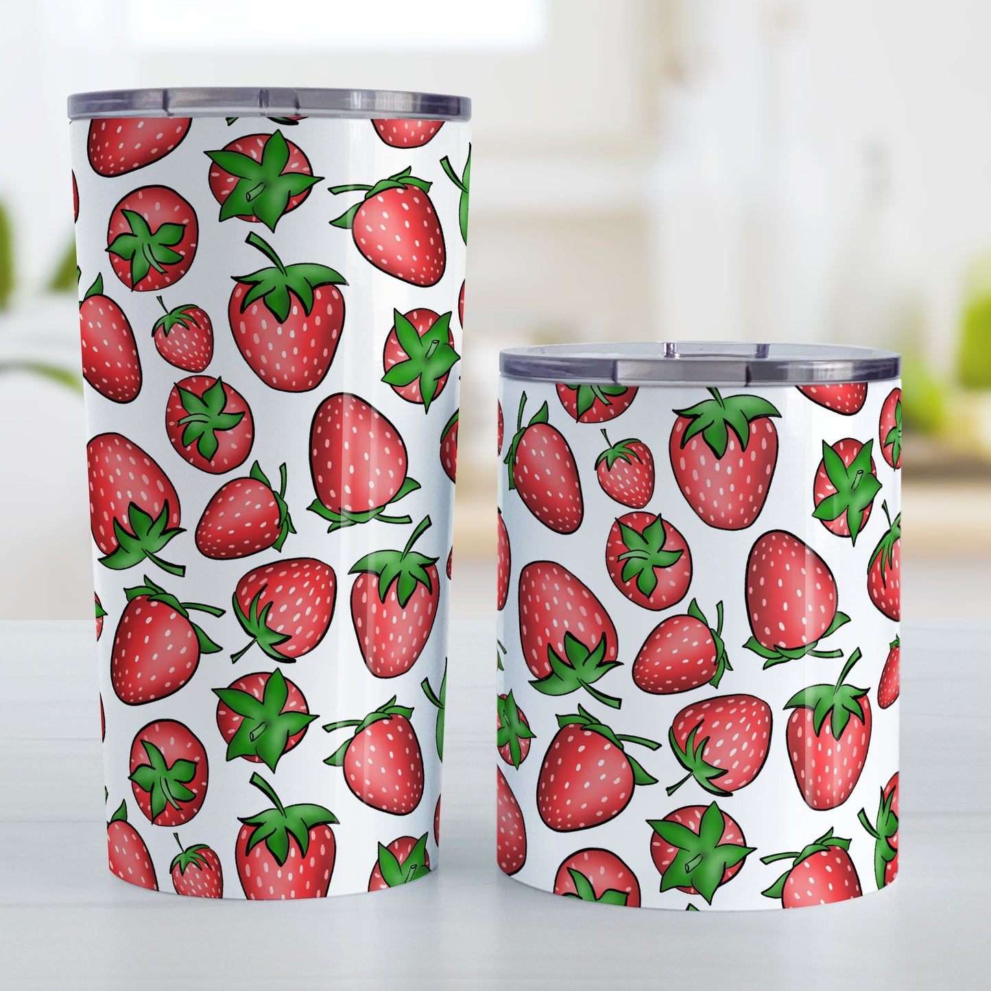 Strawberries Tumbler Cup (20oz and 10oz, stainless steel insulated) at Amy's Coffee Mugs. A tumbler cup featuring a print of hand-drawn strawberries in red and green in an assorted pattern that wraps around the cup. Photo shows both sized cups on a table next to each other.