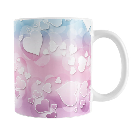 Whimsical Hearts Pattern Mug (11oz) at Amy's Coffee Mugs. A ceramic coffee mug designed with a whimsical pattern of hearts over a gradient bokeh background in pink, blue, and purple that wraps around the mug up to the handle.