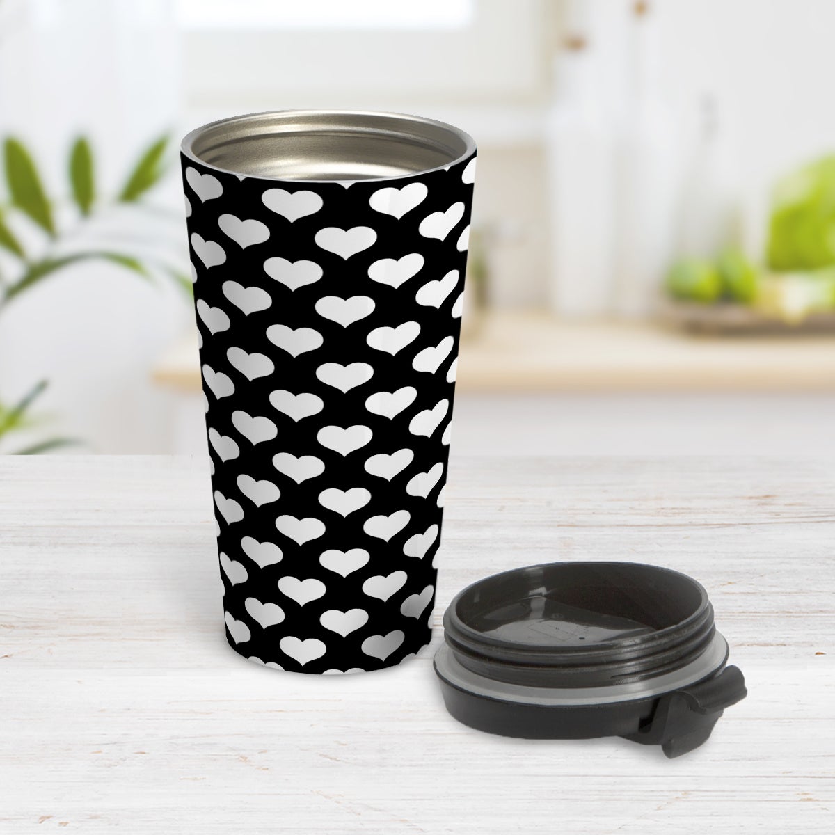 White Hearts Pattern Black Travel Mug (15oz) at Amy's Coffee Mugs. A travel mug designed with white hearts in a polka-dotted style pattern over a black background color that wraps around the mug. Photo shows the mug open on a table with its lid beside it,