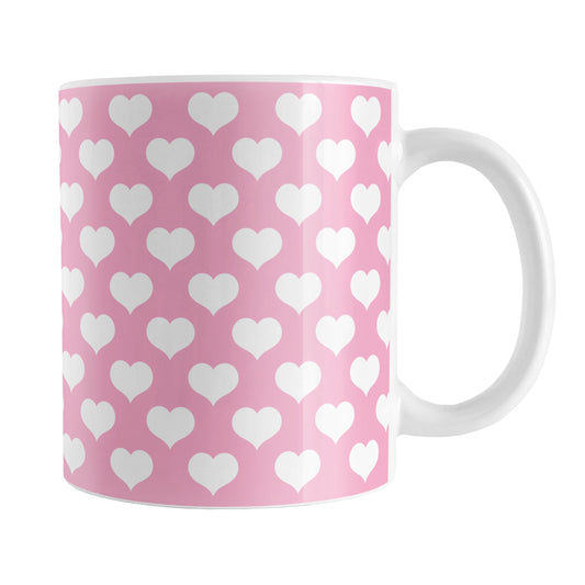 White Hearts Pattern Pink Mug (11oz) at Amy's Coffee Mugs. A ceramic coffee mug designed with white hearts in a polka-dotted style pattern over a pink background color that wraps around the mug up to the handle.
