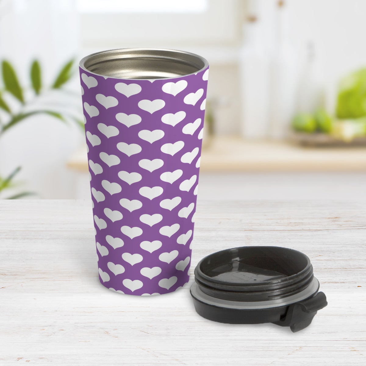 White Hearts Pattern Purple Travel Mug (15oz) at Amy's Coffee Mugs. A travel mug designed with white hearts in a polka-dotted style pattern over a purple background color that wraps around the mug. Photo shows the mug open on a table with its lid beside it.