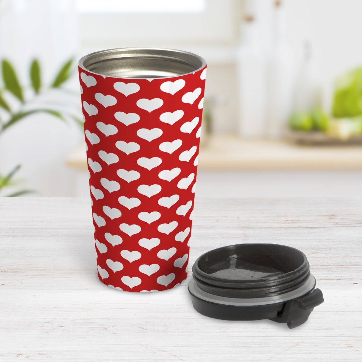 White Hearts Pattern Red Travel Mug (15oz) at Amy's Coffee Mugs. A travel mug designed with white hearts in a polka-dotted style pattern over a red background color that wraps around the mug. Photo shows the mug open on a table with its lid beside it.