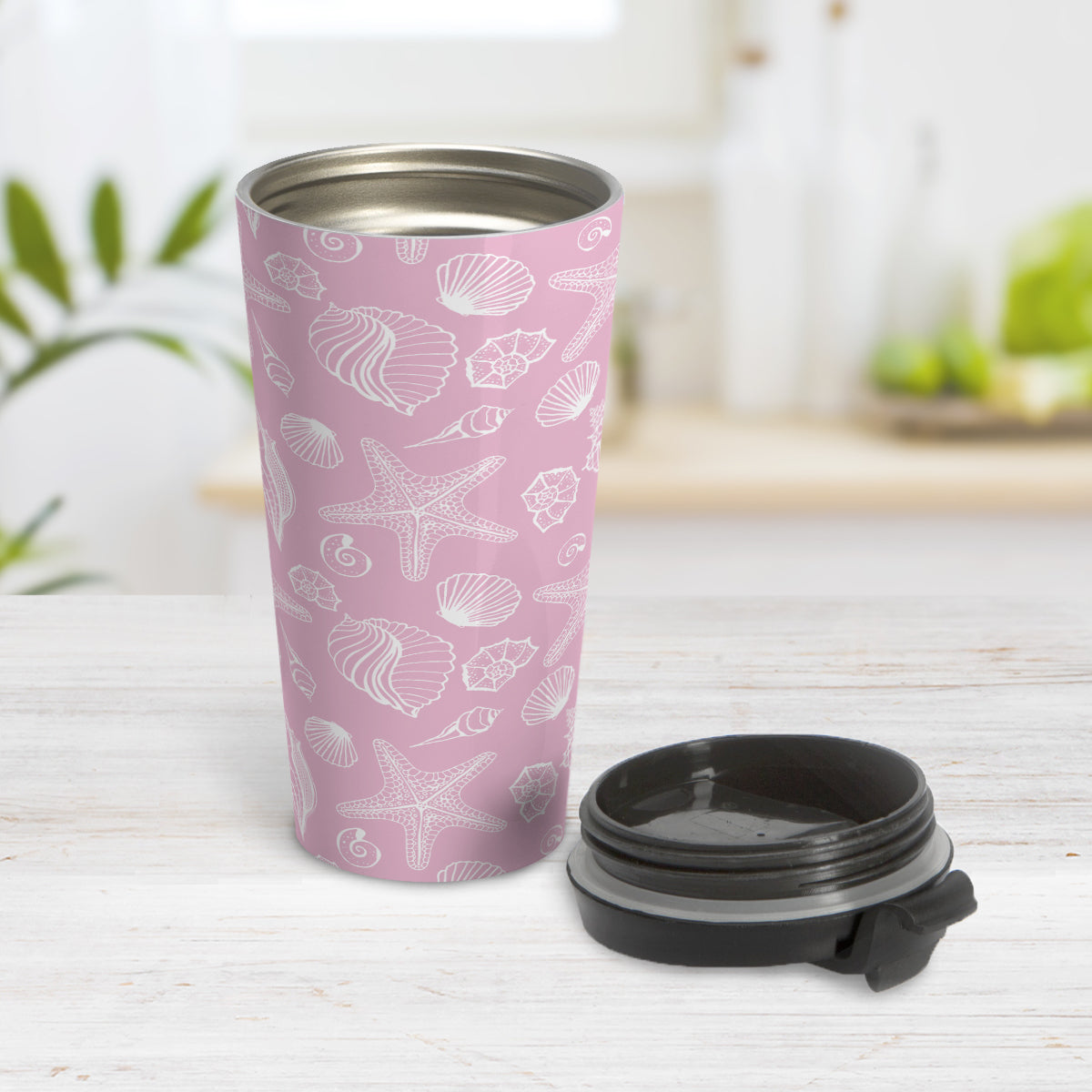 White Seashell Pattern Pink Beach Travel Mug (15oz, stainless steel insulated) at Amy's Coffee Mugs. A travel mug designed with a white seashell line drawing pattern over a pink background that wraps around the travel mug. Photo shows the mug open on a table with its lid beside it.