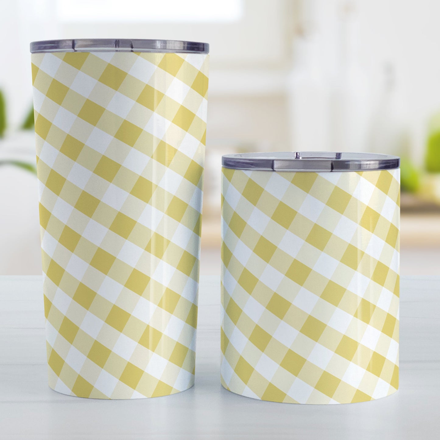 Yellow Gingham Tumbler Cup (20oz and 10oz, stainless steel insulated) at Amy's Coffee Mugs. Tumbler cups designed with a slanted yellow gingham pattern in yellow and white that wraps around the cups. Photo shows both sized cups on a table next to each other.