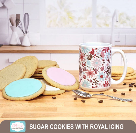 Sugar cookies, some with royal icing, beside the Berry Summer Flowers Coffee Mug on a kitchen island. 