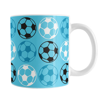 An 11oz white mug with a blue soccer pattern, over a white background