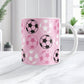 White 11oz mug with pink background and soccer ball pattern, on a marble tabletop