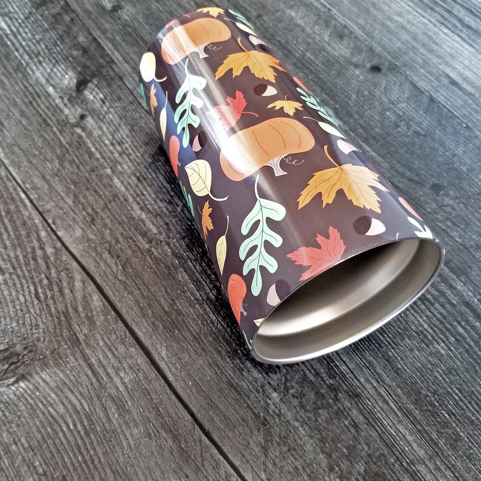 20oz Autumn Pumpkins and Leaves Pattern Fall Tumbler Cup laying on a weathered wood surface.