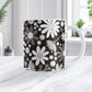 Mug with a floral pattern featuring white and gray flowers on a black background, set on a marble countertop