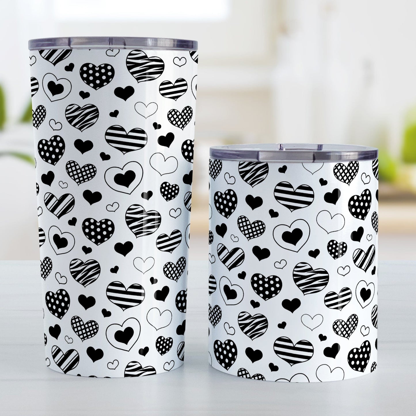 Black Heart Doodles Tumbler Cup (20oz or 10oz) at Amy's Coffee Mugs. Stainless steel tumbler cups designed with hand-drawn black heart doodles in a pattern that wraps around the cups. This cute heart pattern is perfect for Valentine's Day or for anyone who loves hearts and young-at-heart drawings. Photo shows both sized cups on a table next to each other. 