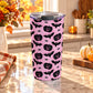 20 oz insulated stainless steel Halloween tumbler cup with black jack-o'-lanterns, bats, spiders, and white spider webs on a pink background, on a granite countertop in a kitchen with fall decor including autumn plants, pumpkins, and an orange plaid tea towel.