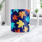 11 oz Blue Fall Leaves Mug with colorful turquoise, orange, and yellow autumn leaves over a deep navy blue background, on a marble countertop in a bright white kitchen.