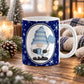 An 11 oz white ceramic mug with a navy blue holiday and winter gnome design, placed on a wooden table surrounded by cozy Christmas decorations like pinecones, evergreen branches, and a knitted blanket.