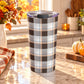 20 oz brown and orange plaid tumbler cup with brown, taupe, gray, white, and orange layered plaid pattern, on a granite countertop in a kitchen with fall decor including autumn plants, pumpkins, and an orange plaid tea towel.