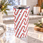 20 oz Christmas tumbler cup with a repeating red and white curved candy cane pattern over a white background, on a granite countertop in a bright kitchen with light rustic winter decor around it.