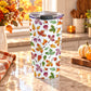 20 oz Changing Leaves Fall Tumbler Cup with orange, yellow, red, green, and purple autumn leaves on white, on a granite countertop in a kitchen with fall decor, including autumn leaves, pumpkins, and an orange plaid tea towel.