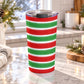 20 oz Christmas tumbler cup with red and green painted brushstroke stripes wrapping around the insulated stainless steel cup, on a granite countertop in a bright kitchen with light rustic decor around it.