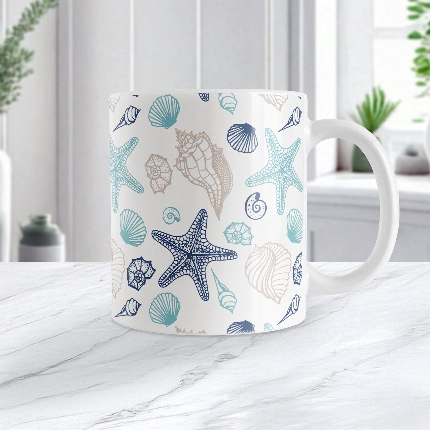 White mug with blue and beige seashell pattern on a white marble surface.