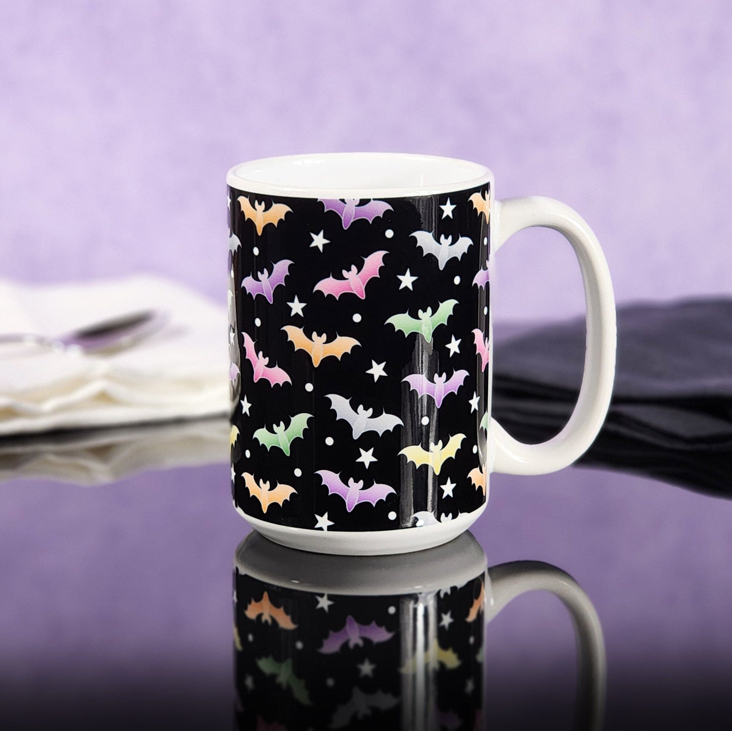 Colorful Bats Mug (15oz) at Amy's Coffee Mugs. Photo shows the mug on a glossy black tabletop with a purple wall background.